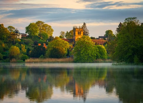 Sunset view of town of Ellesmere in Shropshire with reflection view across the Mere to the Church