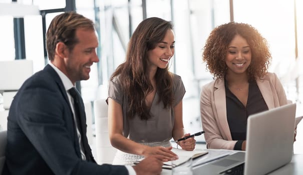 Technology is a huge benefit to their business. a group of businesspeople using a laptop during a meeting in an office