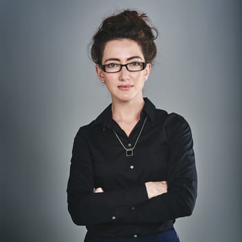 Facing success dead on. Studio portrait of a confident young businesswoman posing against a grey background