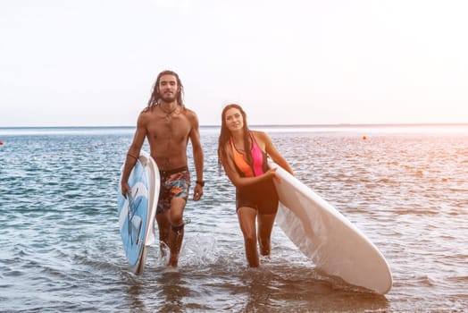 Sea woman and man on sup. Silhouette of happy young woman and man, surfing on SUP board, confident paddling through water surface. Idyllic sunset. Active lifestyle at sea or river