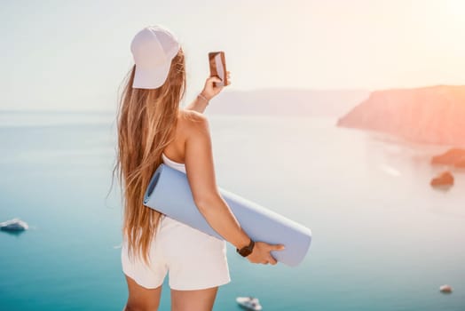 Young woman with black hair, fitness instructor in pink sports leggings and tops, doing pilates on yoga mat with magic pilates ring by the sea on the beach. Female fitness daily yoga concept