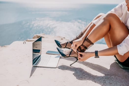 Happy girl doing yoga with laptop working at the beach. beautiful and calm business woman sitting with a laptop in a summer cafe in the lotus position meditating and relaxing. freelance girl remote work beach paradise