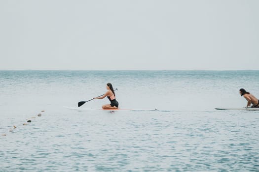 Sea woman and man on sup. Silhouette of happy young woman and man, surfing on SUP board, confident paddling through water surface. Idyllic sunset. Active lifestyle at sea or river