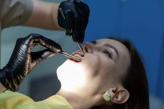 The process of removing braces.Beautiful woman in dental chair during procedure of installing braces to upper and lower teeth. Dentist and assistant working together, dental tools in their hands.