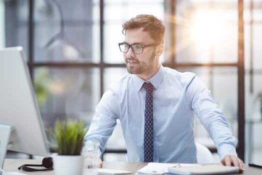 Young cheerful businessman working at office