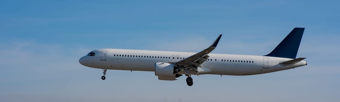 Side view of an airplane landing against a blue sky. Widescreen