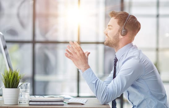 Young handsome male customer support phone operator with headset working in his office