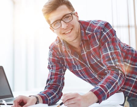 Rear view of a young businessman using laptop at office desk