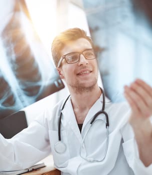 Male doctor in glass radiologist examines x-rays in a medical office.
