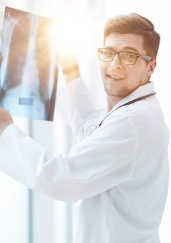 Male doctor in glass radiologist examines x-rays in a medical office.