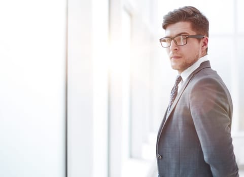 Portrait of a young businessman wearing glasses and standing in office