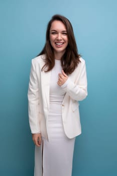 close-up portrait of a smiling european brunette woman with long hair in a white dress and jacket posing on a studio background.