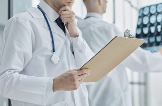 Hands of general practitioner filling paper medical records.