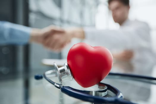 Stethoscope and red heart on wooden table.