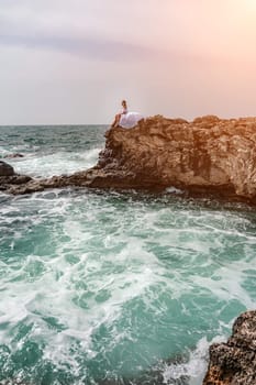 Woman sea white dress. A woman in a storm sits on a stone in the sea. Dressed in a white long dress, waves crash against the rocks and white spray rises