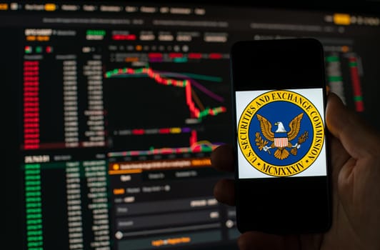 Kyiv, Ukraine - 06 June 2023: Man holds a smartphone with SEC logo against the background falling Bitcoin chart on Binance - crash. S.E.C. Accuses Binance of Mishandling Funds and Lying to Regulators