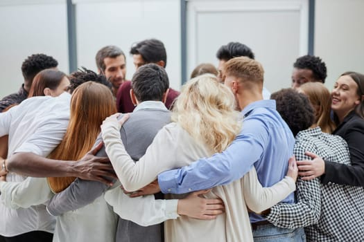 Team of young people hugging in the office.