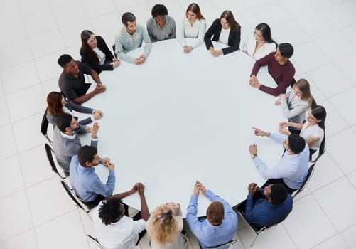 Businessmen or office workers are sitting at a round table in casual clothes.