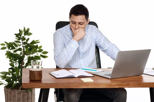 sad businessman using laptop, sitting on chair at desk, having problems thinking about troubles in office