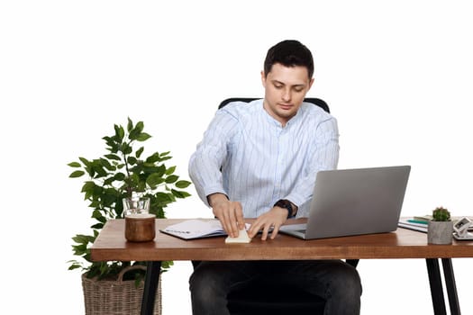 businessman in blue shirt taking notes, using laptop computer on white background