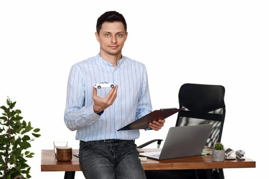 Successful caucasian businessman holding a toy car while standing at desk. Car dealerships offer car . Car insurance