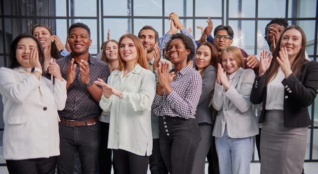 Smiling business colleagues clapping hands standing in the hallway
