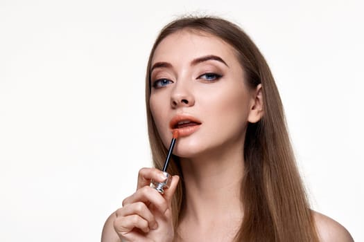 pretty young woman testing nude lip gloss isolated on white background