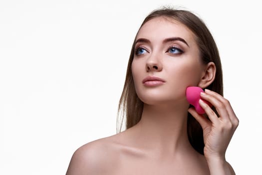 attractive young woman using pink cosmetic sponges isolated on white background. copy space