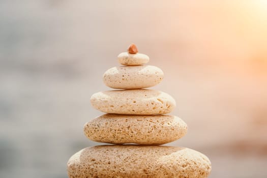 Pyramid stones on the seashore with warm sunset on the sea background. Happy holidays. Pebble beach, calm sea, travel destination. Concept of happy vacation on the sea, meditation, spa, calmness.