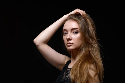 sexy brunette woman with long hair in black dress on black background. copy space