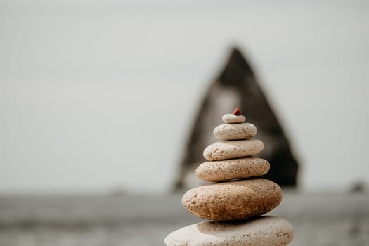 Pyramid stones on the seashore with warm sunset on the sea background. Happy holidays. Pebble beach, calm sea, travel destination. Concept of happy vacation on the sea, meditation, spa, calmness.