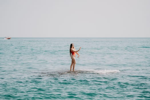 Woman sea yoga. Back view of free calm happy satisfied woman with long hair standing on top rock with yoga position against of sky by the sea. Healthy lifestyle outdoors in nature, fitness concept.