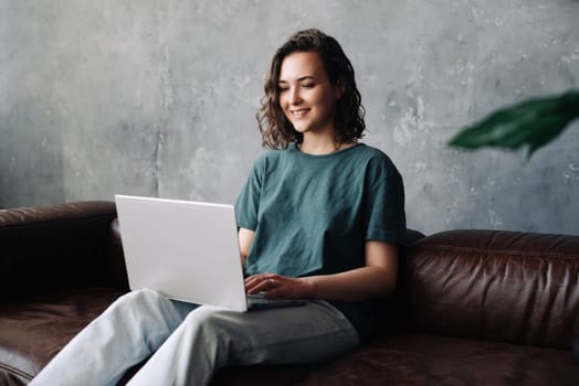 Productivity and Independence: Young Woman Engages in Remote Work and Study, Utilizing Laptop in the Comfort of Home. Embracing the Benefits of Freelancing, Business Ventures, and a Flexible Lifestyle