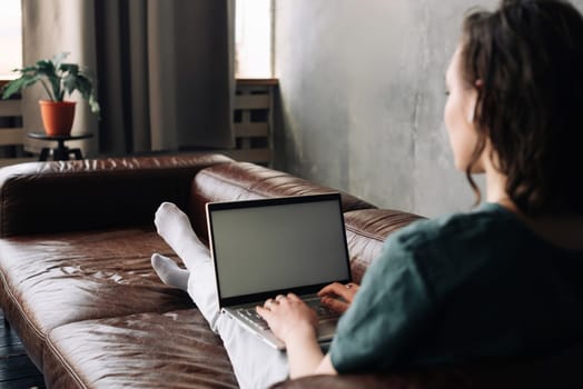 Young Woman Utilizes Laptop with Blank White Screen at Home. Explore the Versatility of Freelancing, Student Lifestyle, Education, Web Conferencing, Video Calls, Technology, and Online Shopping