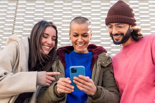three young friends smiling happy and enjoying the moment using together a mobile phone, concept of technology of communication and modern lifestyle