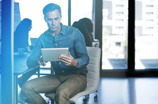 Communication and the flow of information have changed. a businessman using a digital tablet with his colleagues blurred in the background