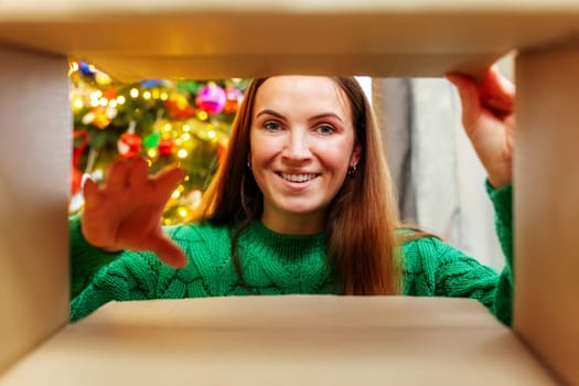 Young woman opening Christmas present, view from inside the box. Merry Christmas and Happy Holidays