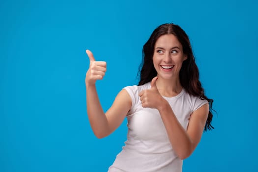 Smiling woman giving thumbs up on the blue background