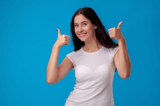 Smiling woman giving thumbs up on the blue background