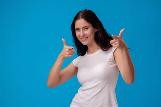 Smiling woman giving thumbs up on the blue background