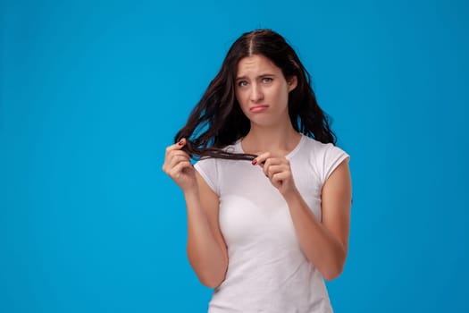 Sad woman is pulling her hair on the blue background