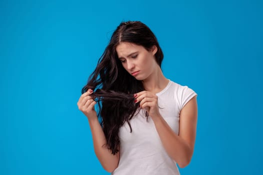 Sad woman is pulling her hair on the blue background