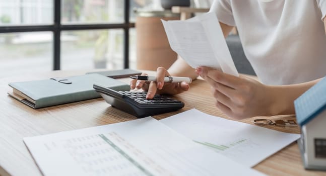 Young woman checking bills, taxes, bank account balance and calculating expenses in the living room at home.