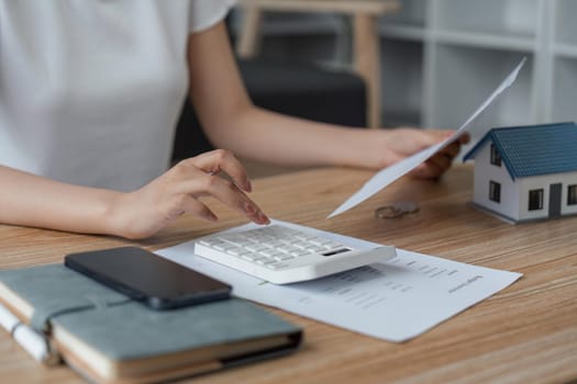 Young woman checking bills, taxes, bank account balance and calculating expenses in the living room at home.