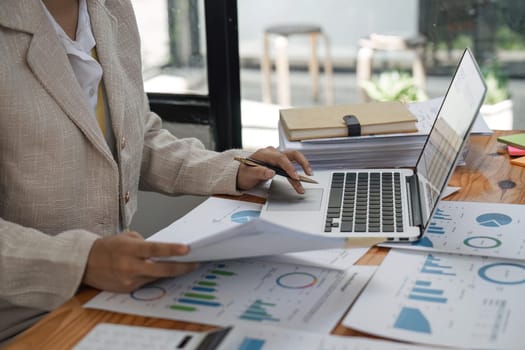 Close-up woman hand press laptop to analyzing the company's financial results On the wooden table in the office and business work background, tax, accounting, statistics, and analytical research.