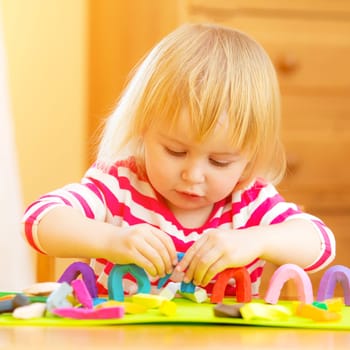 Cute girl playing with plasticine at home