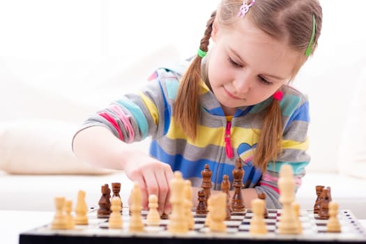 Cute little girl playing chess at home
