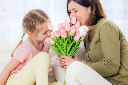 Happy mom and girl enjoying Mothers day on the couch, relaxing