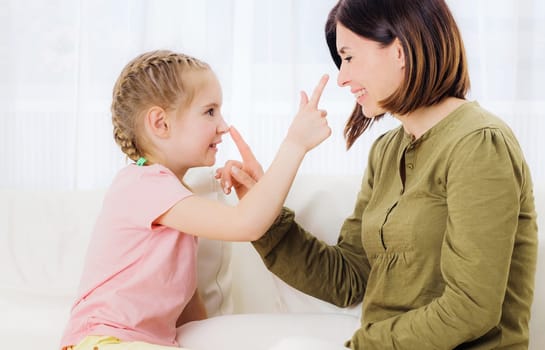 Lovely daughter and smiling mother are playing and gesturing