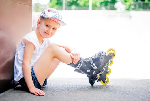 Cute smiling little girl on roller skates in roller park